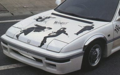 White Honda car with Boøwy band graphics on hood, Japanese text H X T on side; street view.