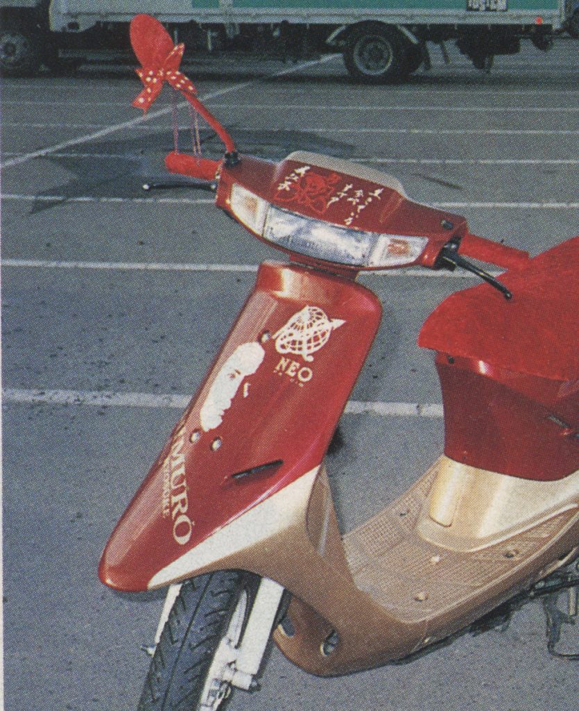 Red and gold Honda Dio AF18 scooter in a parking lot with floral and geometric decals, featuring the text Nao-kun and Neo.