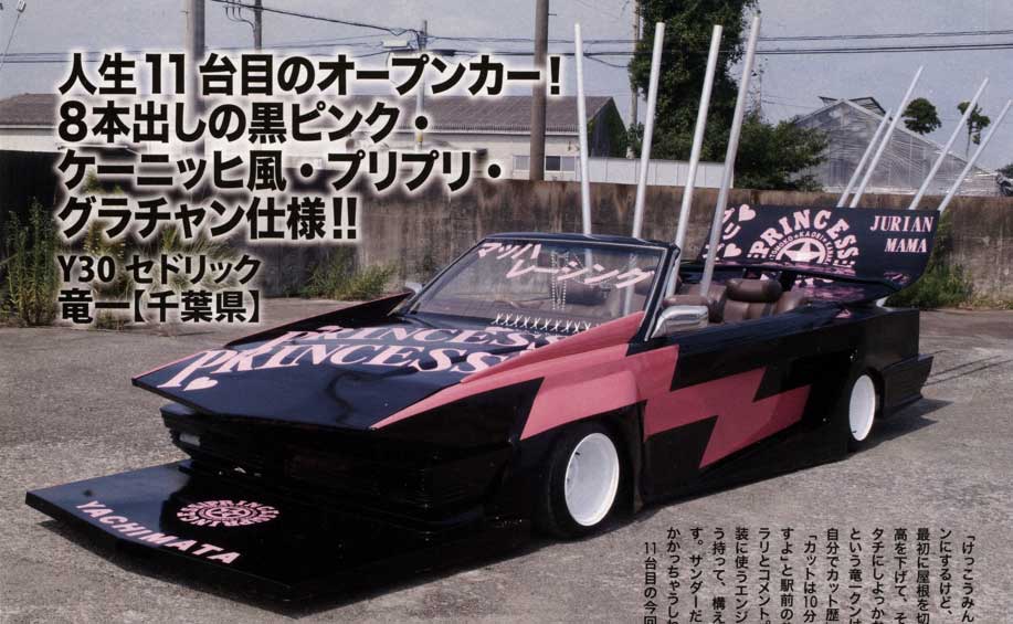 Customized black and pink convertible car with Princess decal parked outdoors with text in Japanese above it.