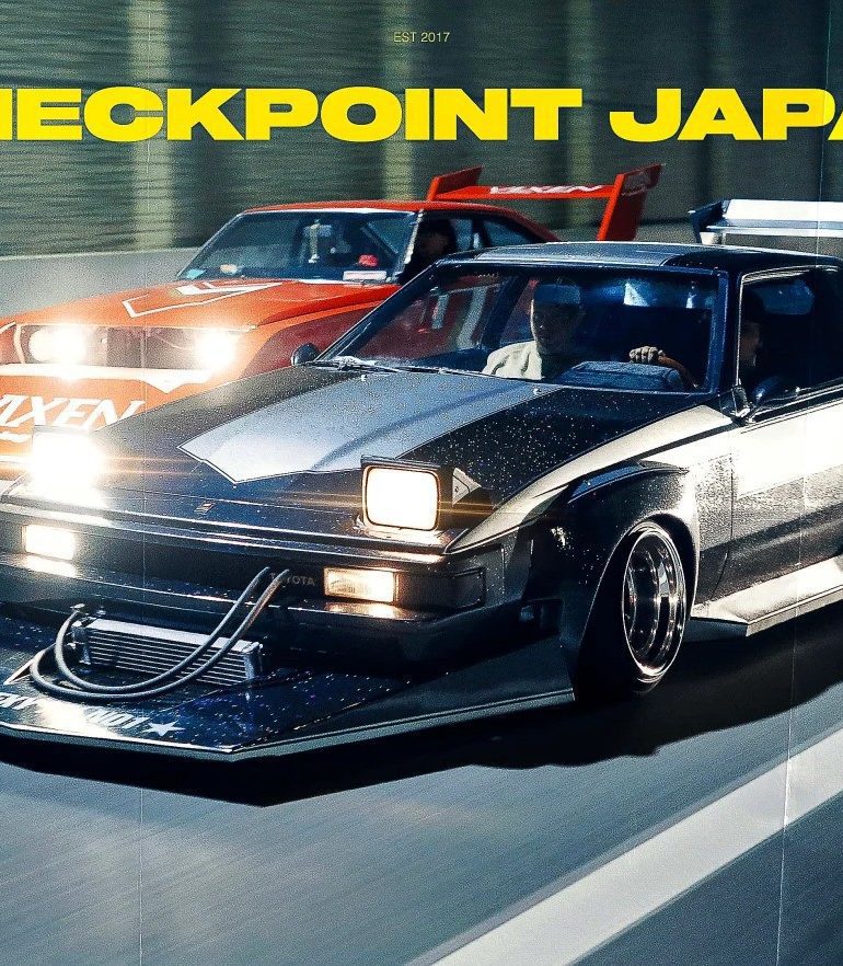 Modified Toyota Celica Supra racing on highway at night, text CHECKPOINT JAPAN in bold yellow font.