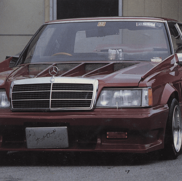 Customized vintage Mercedes-Benz with aggressive body kit and low stance; Japanese license plate reads ナツロード meaning Nat Road.