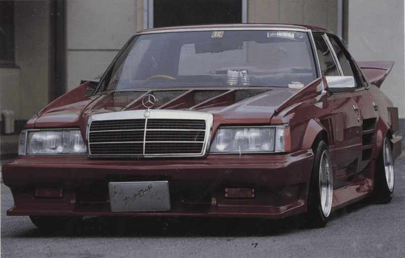 Customized vintage Mercedes-Benz with aggressive body kit and low stance; Japanese license plate reads ナツロード meaning Nat Road.