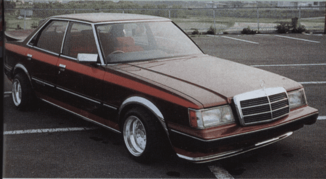 Vintage red Toyota GX61 Mark ii sedan with modified body kit, Mercedes Benz 190e grille, and SSR Mark 1 wheels parked in an open lot.