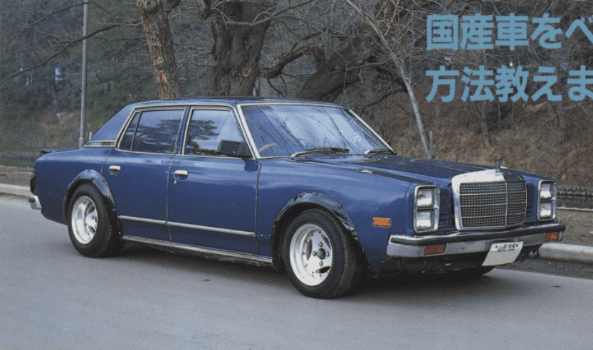 Vintage blue four-door sedan in park, Japanese text overhead translating to “How to spot domestic cars.” Mazda Luce LA4 with Mercedes grille, advan tri-spoke a3a wheels.