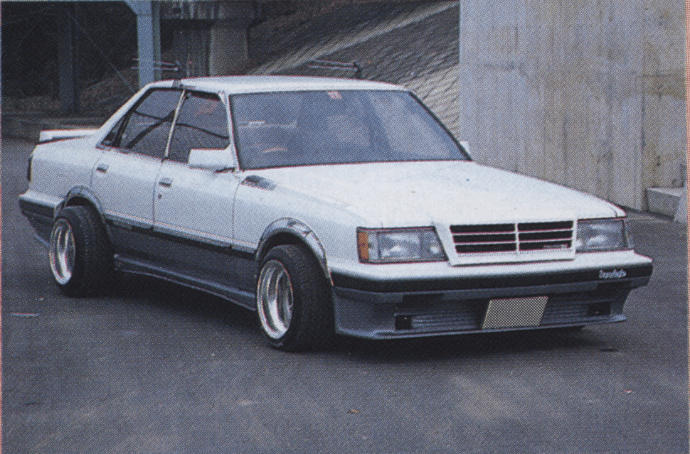 Alt text: Modified white Japanese sedan Toyota GX61 Mark ii with wide tires Hamitai and custom body kit on street.(Note: The Japanese text トヨタ translates to Toyota, but the specific make and model are not included in the alt text for brevity and relevance to SEO practices.)