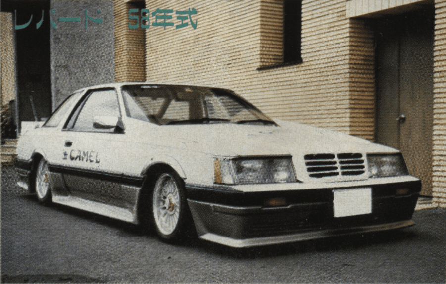 Vintage Japanese car, 1983 Nissan F30 Leopard 58th-hand model, beige, showcased in front of a modern brick building.