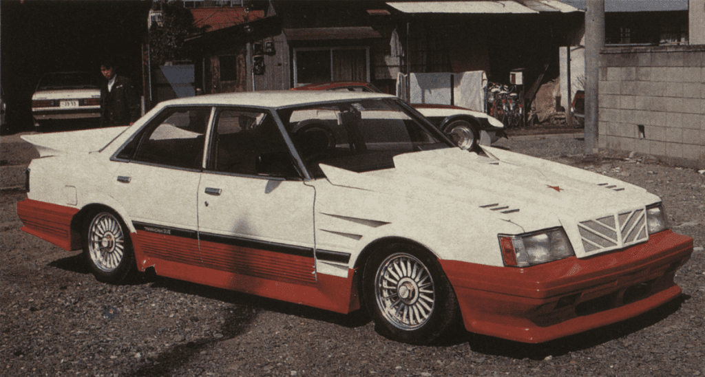 Modified Japanese sedan Toyota GX61 Mark ii with white and red paint, parked outdoors. The Japanese text ツインカム2.2 translates to Twin Cam 2.2.