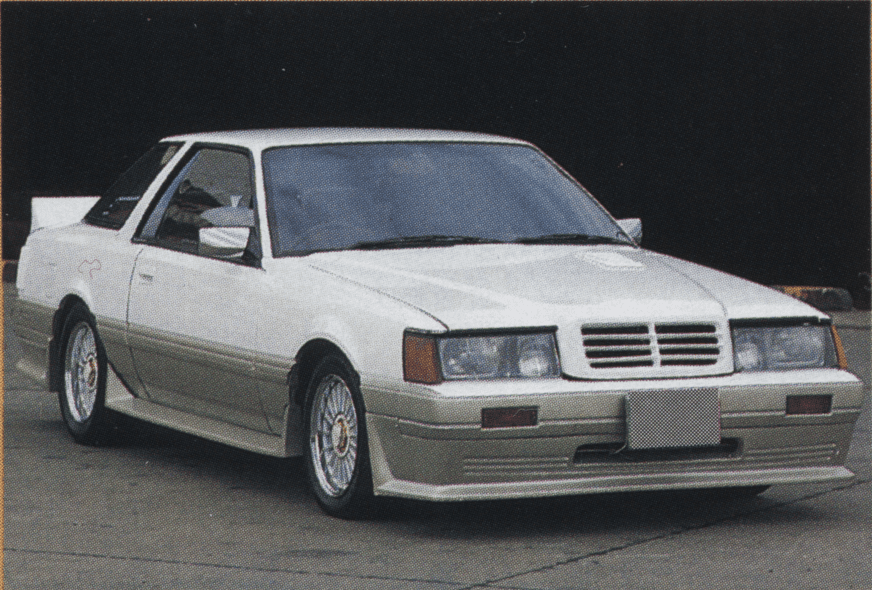 Vintage white and beige Nissan F30 Leopard coupe with fiberglass FRP Mecedes-Benz style grille and a custom body kit parked on the pavement.