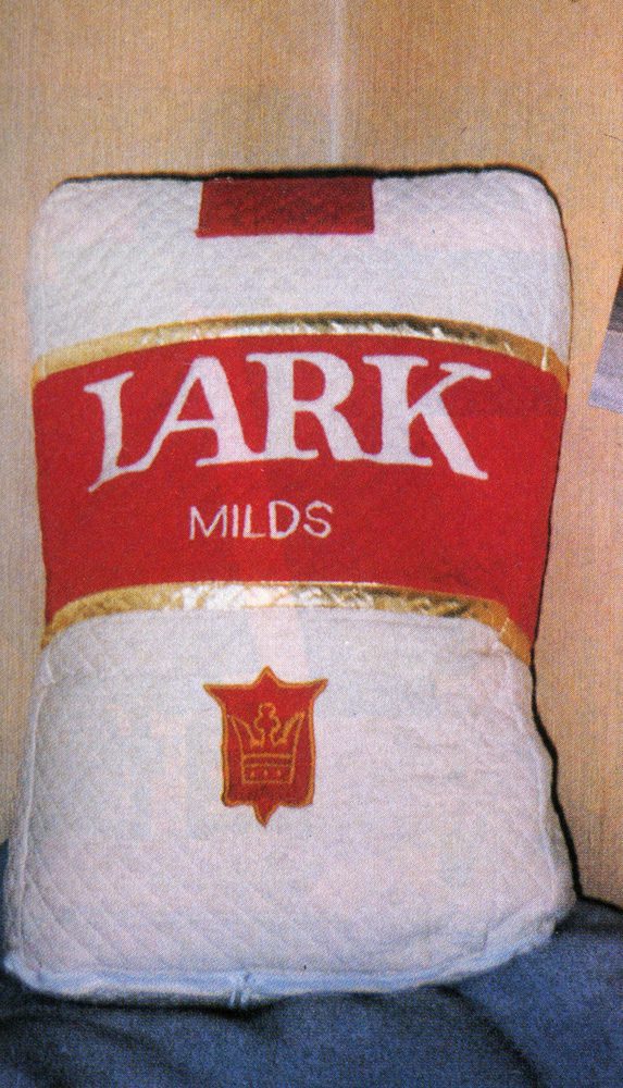 Pillow designed like a Lark Milds cigarette pack with a red and gold accent.