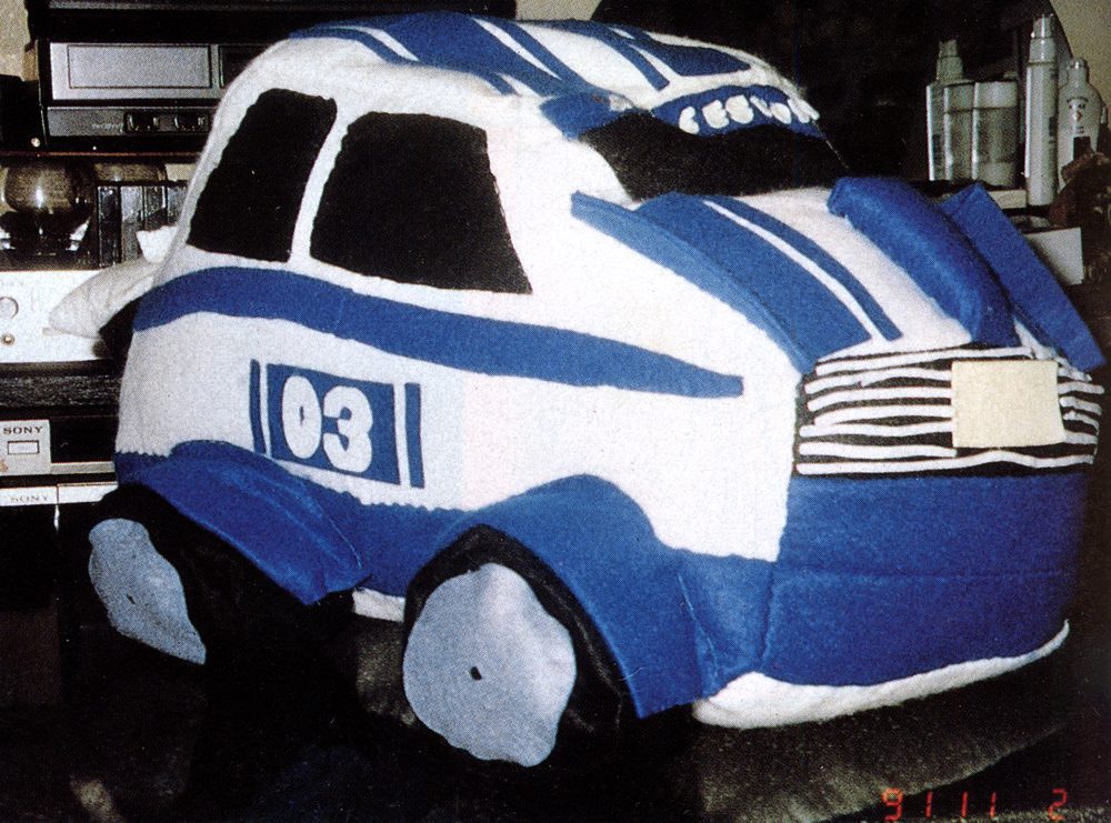 Plush toy car with blue racing stripes and 03 on its side. Cozy and unique handmade design.