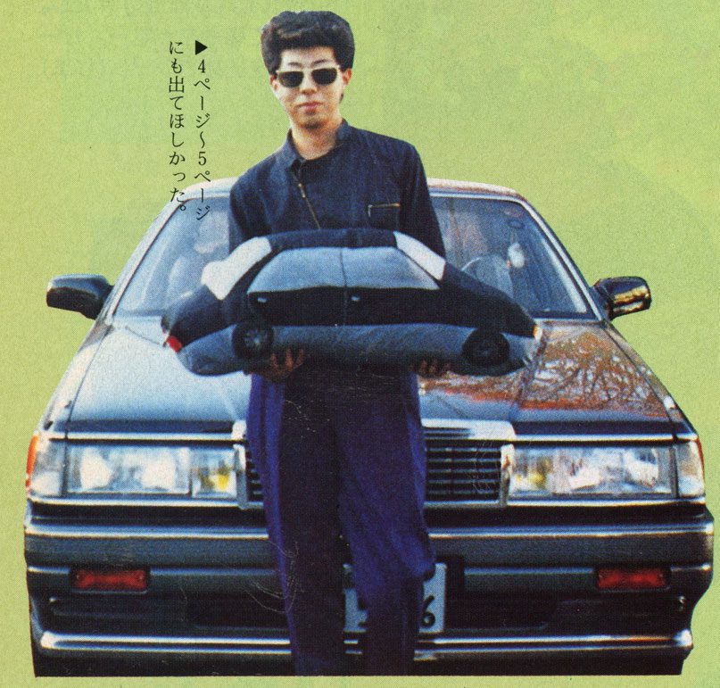 Young man in sunglasses holding a car cushion in front of a sedan. Japanese text: I wanted to be in pages 4 to 5.