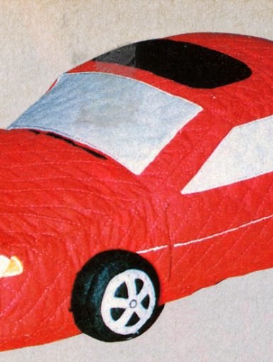 Toy red car with a quilted design, featuring realistic details on wheels and windows, on a beige background.