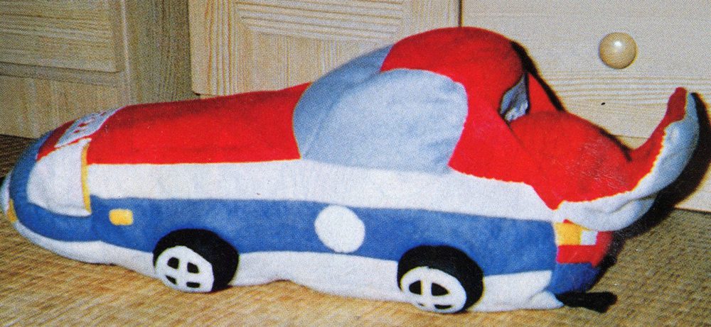 Plush toy car with colorful design, featuring a red, blue, and gray pattern, displayed on a wooden surface.