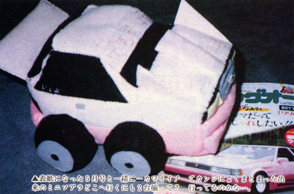 Plush toy car with Japanese magazine, showcasing cute design and playful theme.