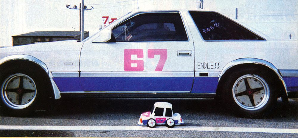 White car number 67 with a matching toy car on the road, featuring ENDLESS and Japanese text translating to Sayonara!!.
