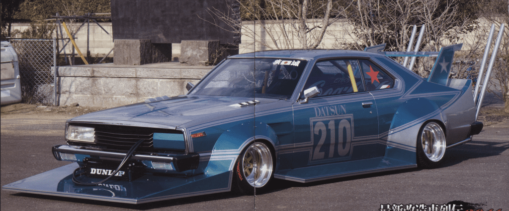 Vintage blue Datsun 210 with custom modifications and decals, parked outdoors on a sunny day.