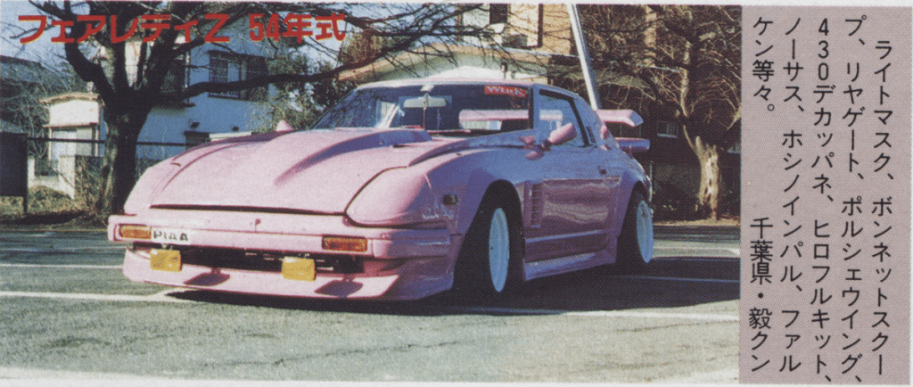 Vintage pink custom car with a large spoiler and unique body kit parked outdoors.