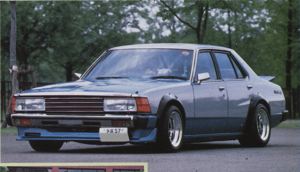 Vintage blue sedan parked on a road, showcasing a classic car design with custom modifications.