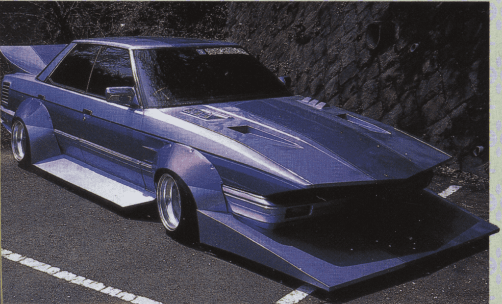 Customized purple car with wide body kit, parked on a street, showcasing unique modifications.