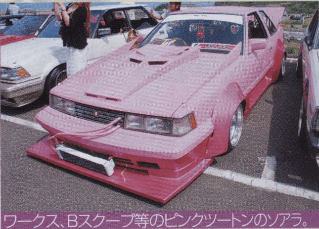 Customized pink car with unique body kit and modifications on display at a car show.