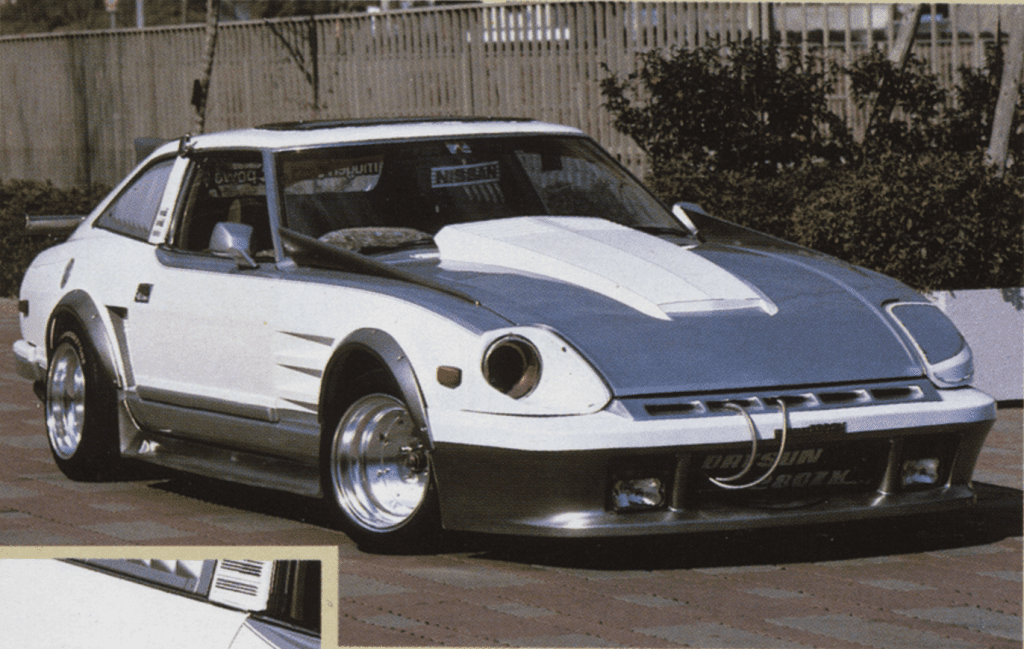 Customized classic car with wide-body kit and polished wheels parked outdoors.