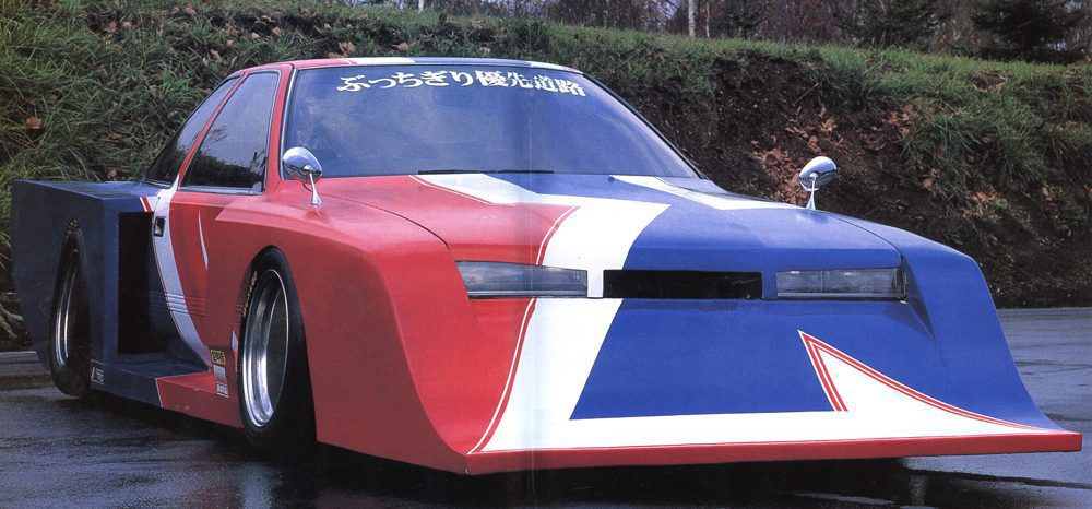 Futuristic custom car with a bold red, white, and blue design parked on wet pavement.