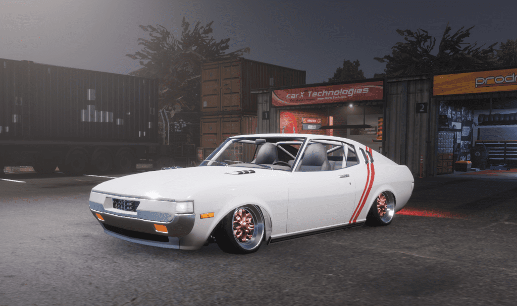 Classic white sports car with red stripes parked at a garage, featuring custom pink rims at night.