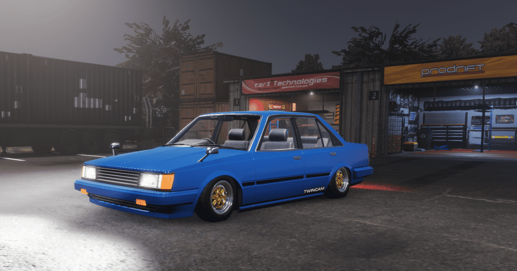 Blue classic sedan parked in a garage at night, with custom wheels and twin cam engine branding.