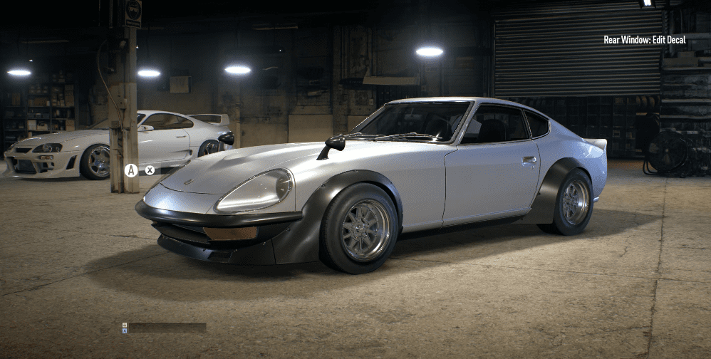 Classic silver sports car in a dimly lit garage, showcasing sleek design and polished bodywork.