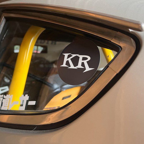 KR sticker on a car window with yellow roll cage visible inside.