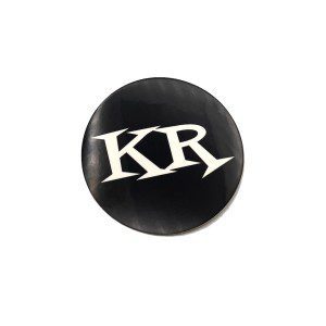 Black circular sticker with bold white letters KR in a stylish font.