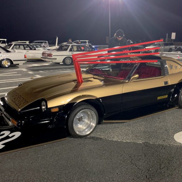 Custom vintage Nissan sports car at night car meet, featuring distinctive body modifications and bold styling.