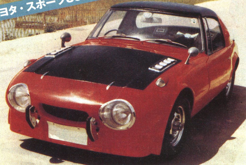 Vintage red sports car with black hood, classic design, parked outdoors.