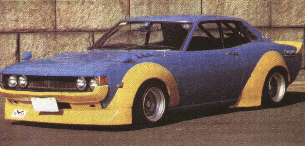 Vintage blue and yellow classic car with custom body kit, parked outdoors.