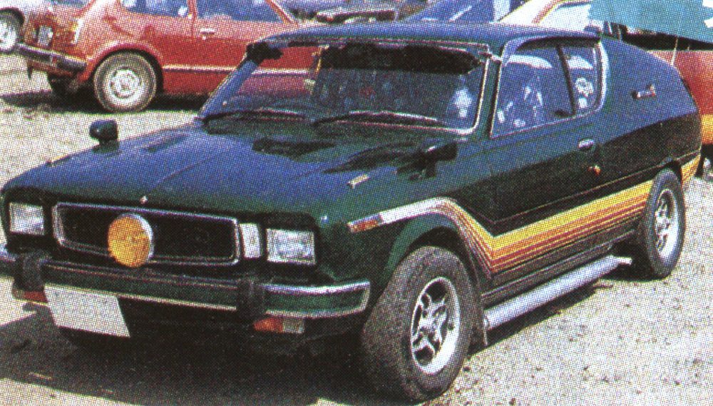 Vintage modified car with retro design and colorful stripe details, parked on gravel with another vehicle in the background.