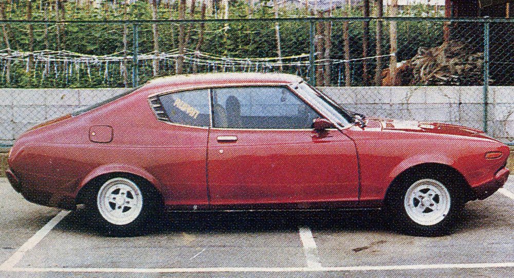 Vintage red coupe car parked in a lot, side view with retro design elements.