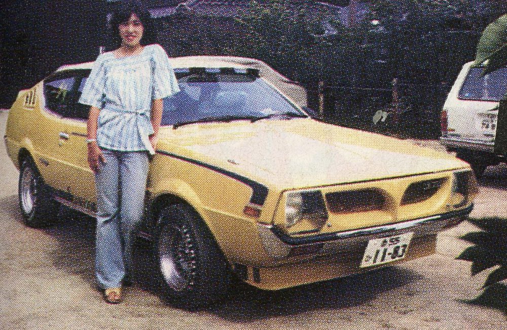Woman poses with a classic yellow sports car from the 1970s, showing vintage style and automotive history.