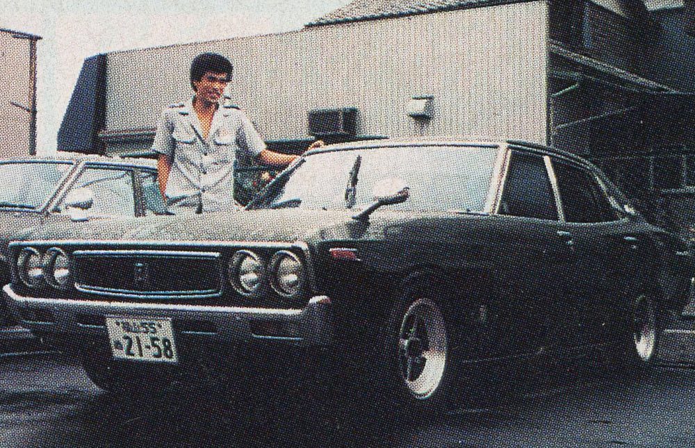 Vintage Nissan Skyline sedan parked with person standing beside it.