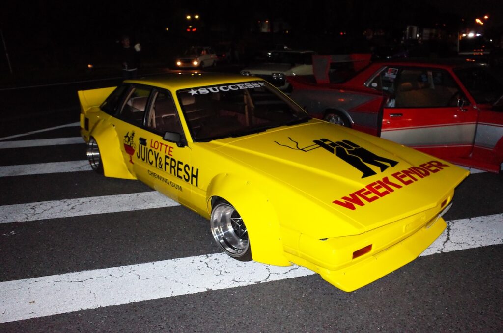 Yellow sports car with Weekender branding parked on a road at night, featuring Lotte Juicy & Fresh design.