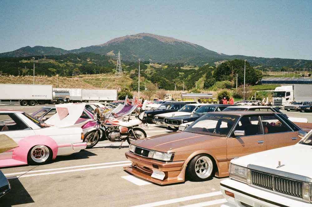 Custom vintage cars and motorcycles at a scenic mountain car meet on a sunny day.
