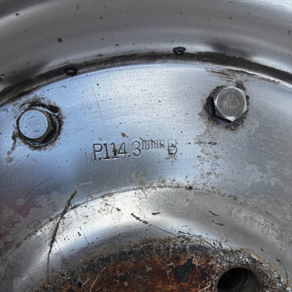 Close-up view of a metallic wheel rim with bolt pattern marking P.114.3mm.