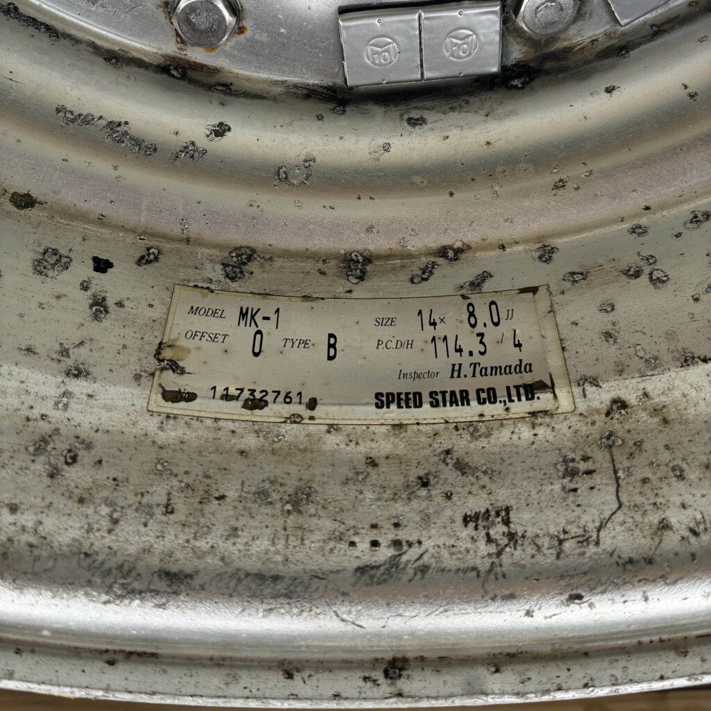 Close-up of worn metal wheel rim showing Speed Star Co., Ltd. label with specifications and inspector details.