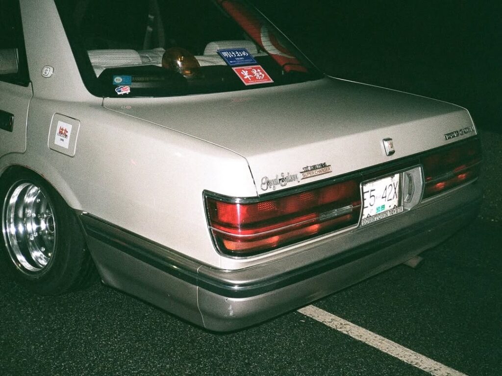 Vintage Toyota car with custom stickers and sleek wheels at night.