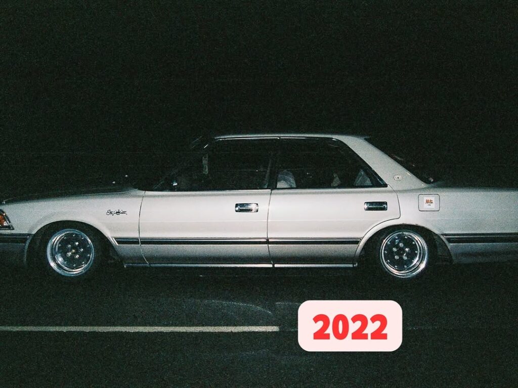 Classic silver sedan at night with custom wheels, 2022 overlay in corner.