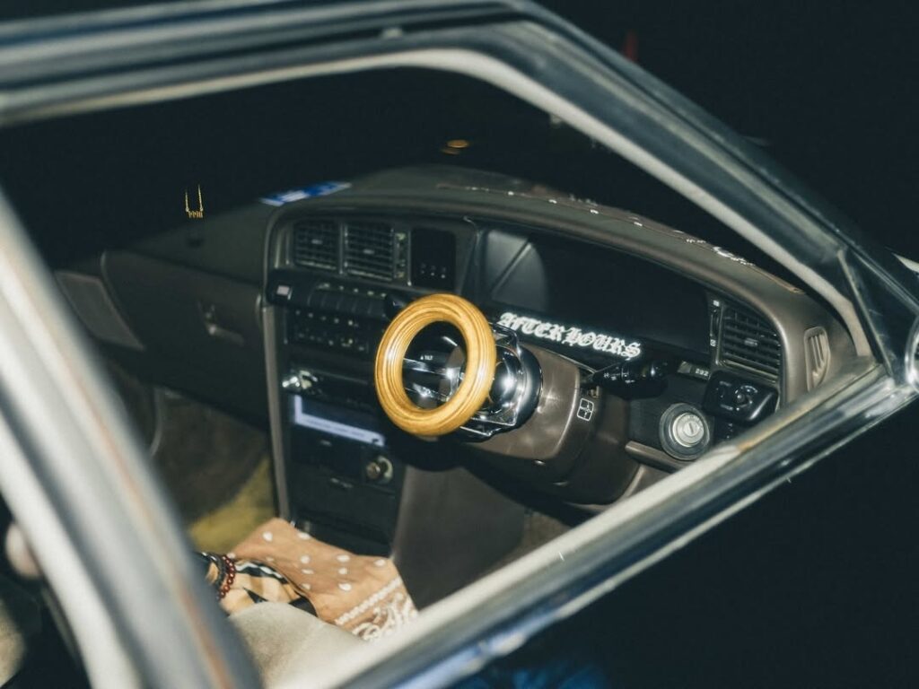 Wooden steering wheel inside vintage car, dashboard view at night.