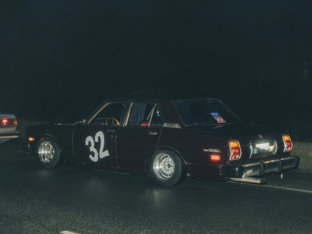 Vintage car with number 32 on the side, parked on a dimly lit road at night.