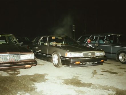 Vintage cars parked at night, showcasing classic design and style in a dimly lit setting.