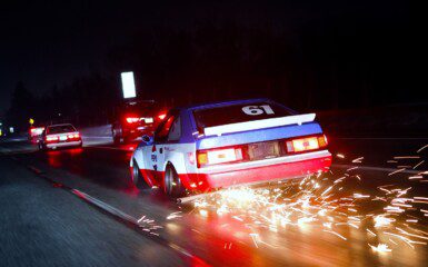 Racing car driving at night with sparks flying, creating a dynamic and thrilling motorsport scene.